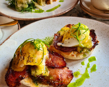 eggs and bacon on a muffin on a plate in a restaurant